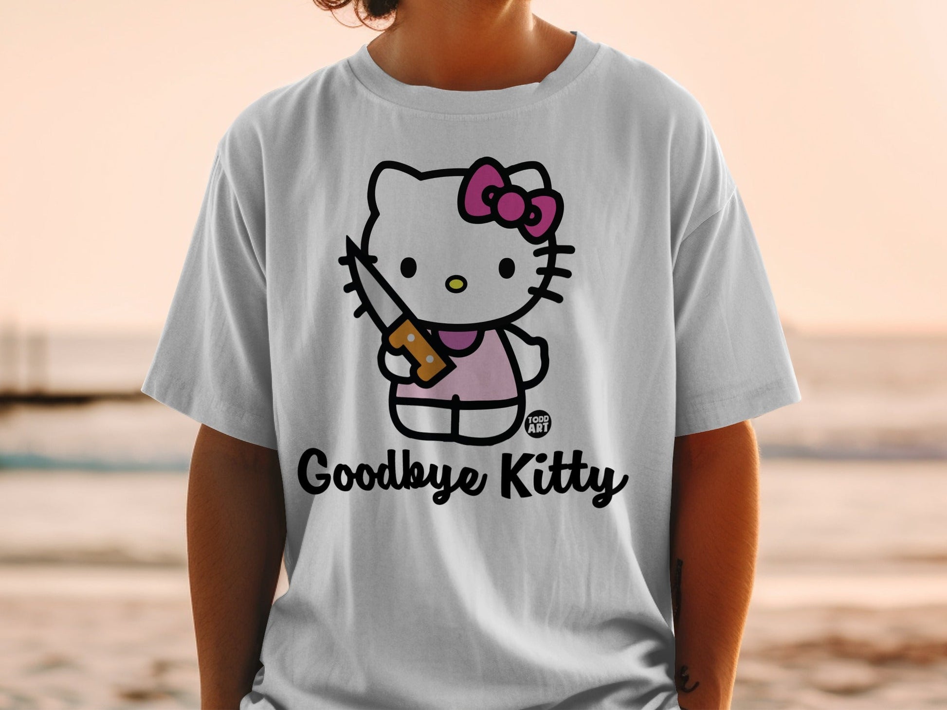 White t-shirt with Hello Kitty character holding a knife, text "Goodbye Kitty".