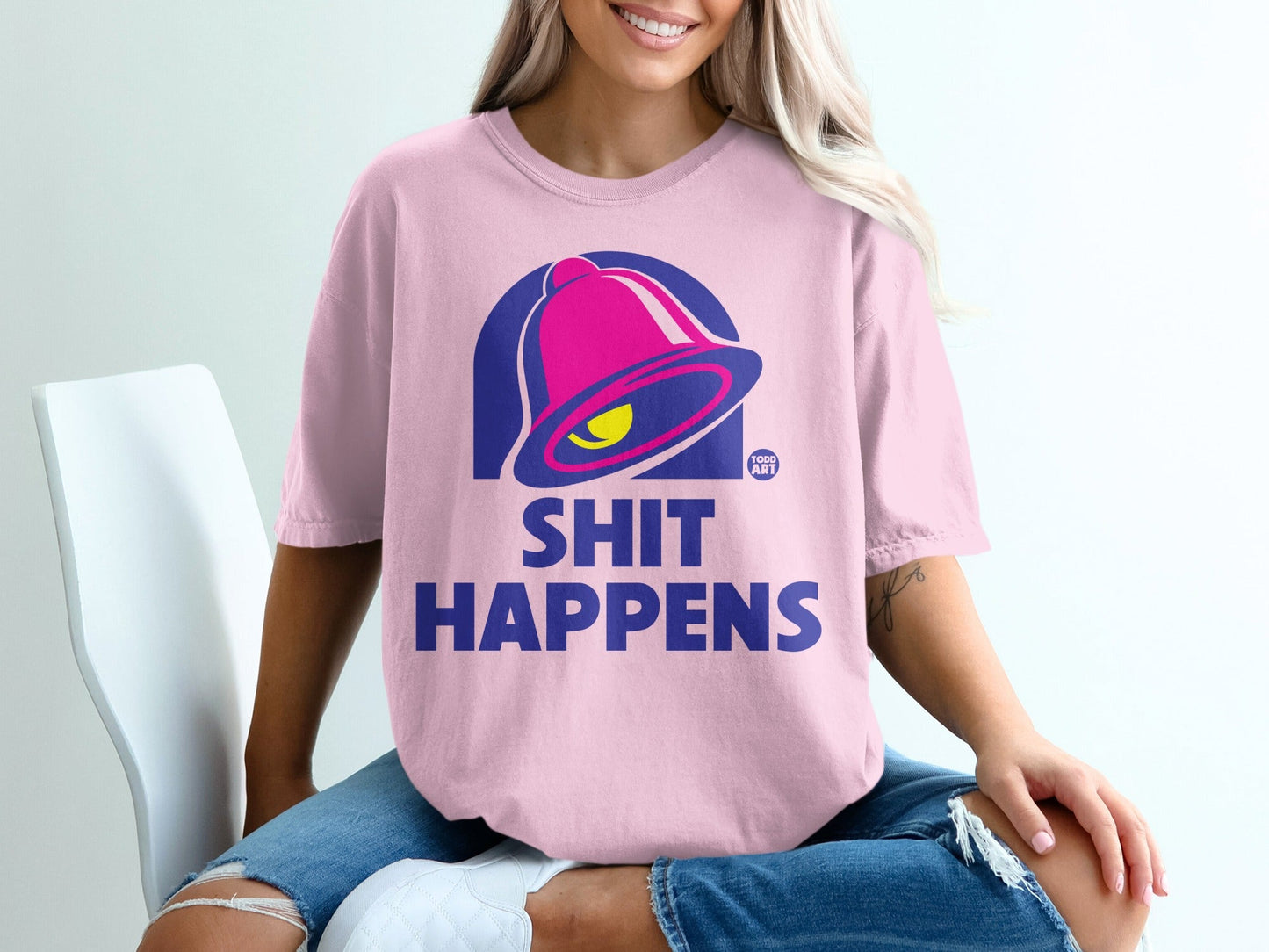 Pink t-shirt with blue bell logo and "SHIT HAPPENS" text.