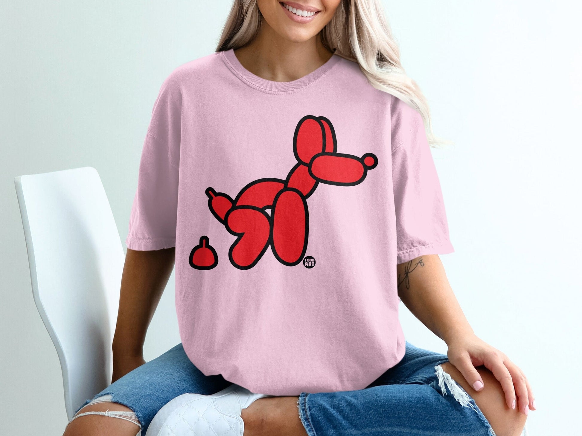 Pink t-shirt with a red balloon dog and a poop emoji.
