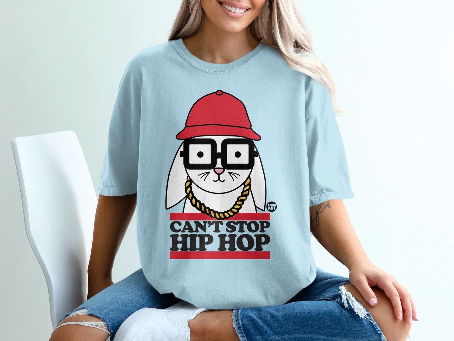 Light blue t-shirt with cartoon rabbit wearing glasses, red hat, and gold chain, text reads "CAN'T STOP HIP HOP".