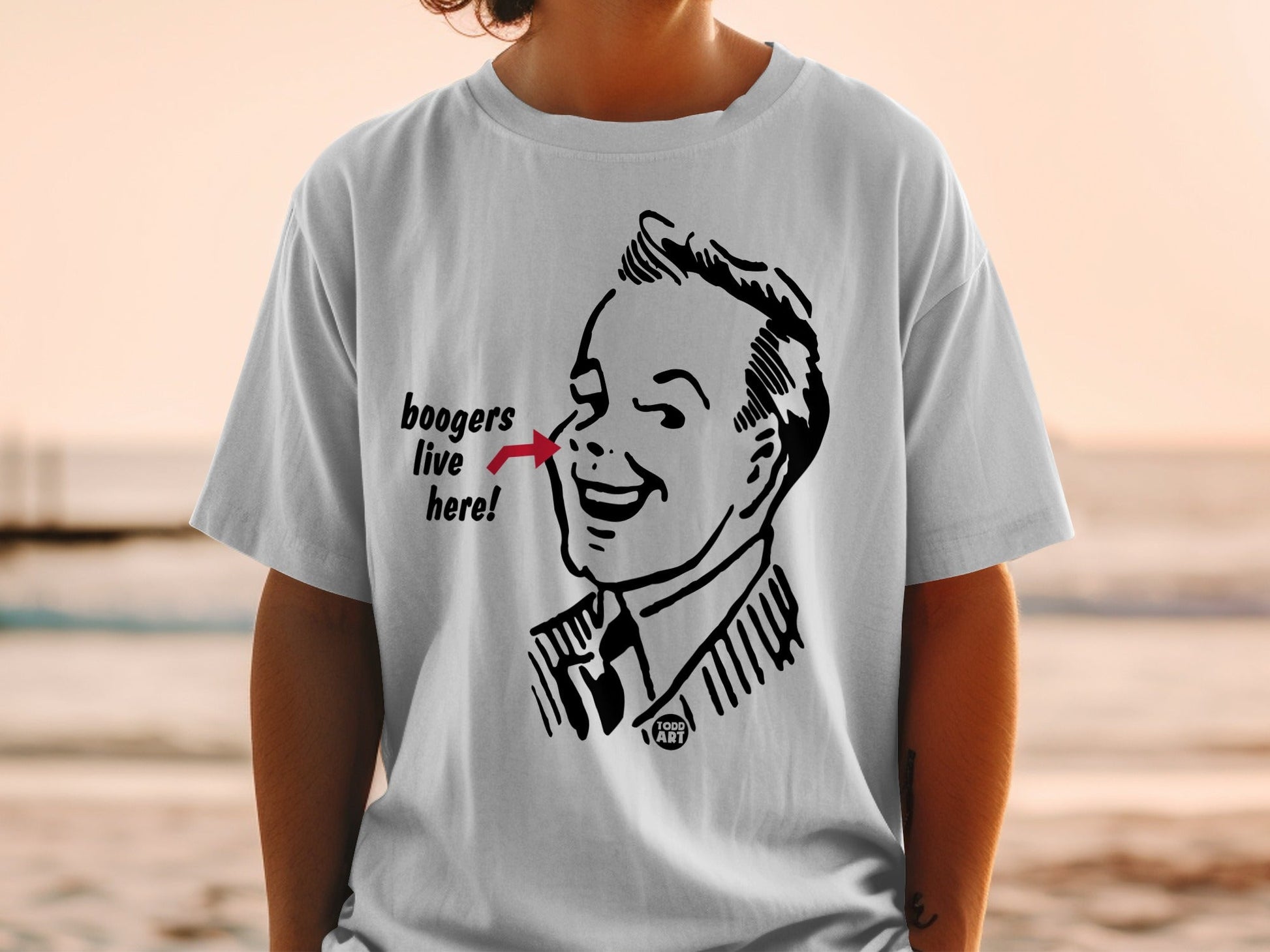 White t-shirt with cartoon man pointing to nose, saying "boogers live here!".