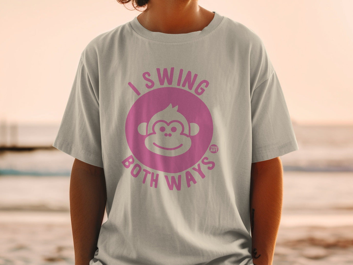 Pink text on a grey t-shirt reads "I swing both ways" with a monkey logo.