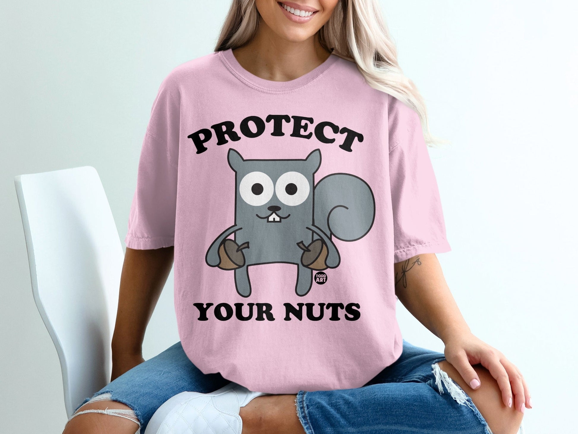 Pink t-shirt with "PROTECT YOUR NUTS" and a cartoon squirrel holding acorns.
