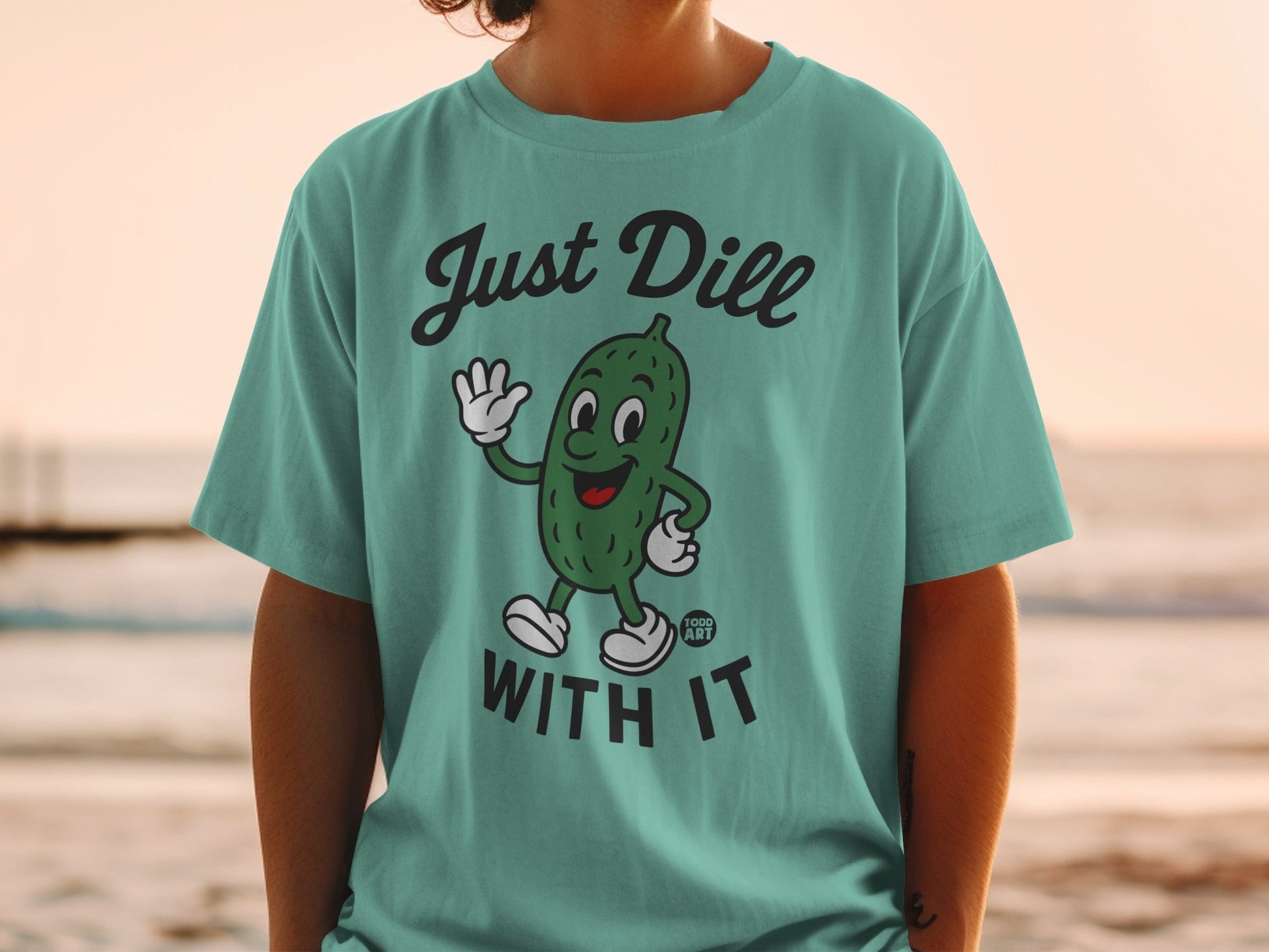 Teal t-shirt with cartoon pickle saying "Just Dill With It".