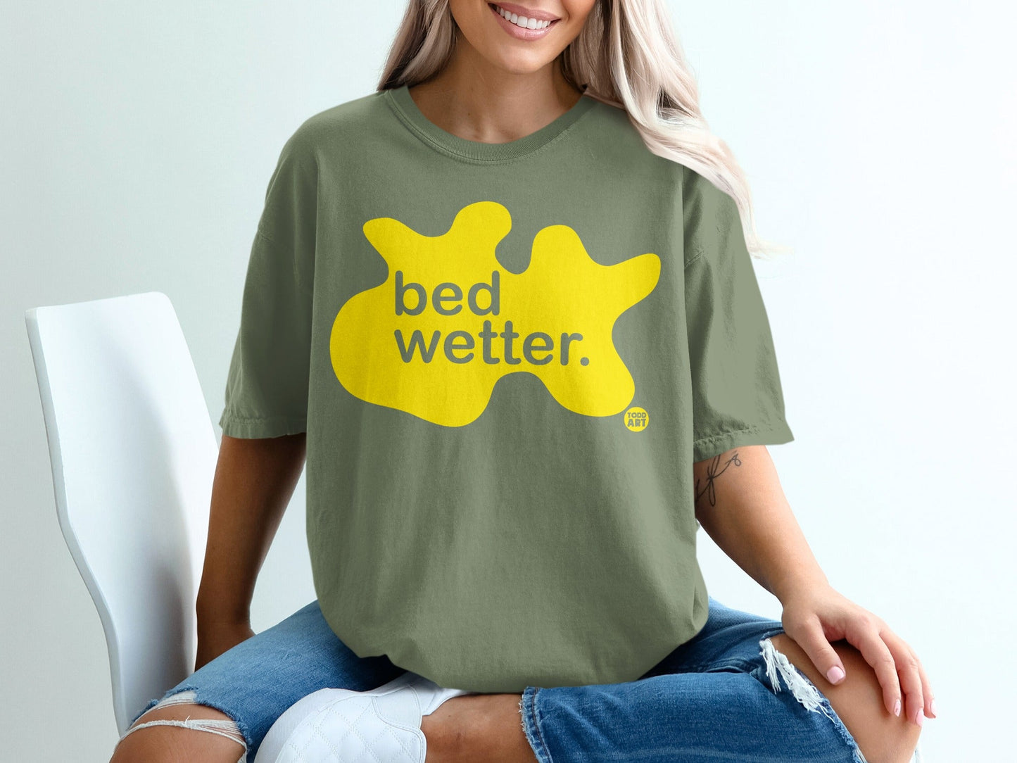 Olive green t-shirt with yellow "bed wetter." text and small logo.