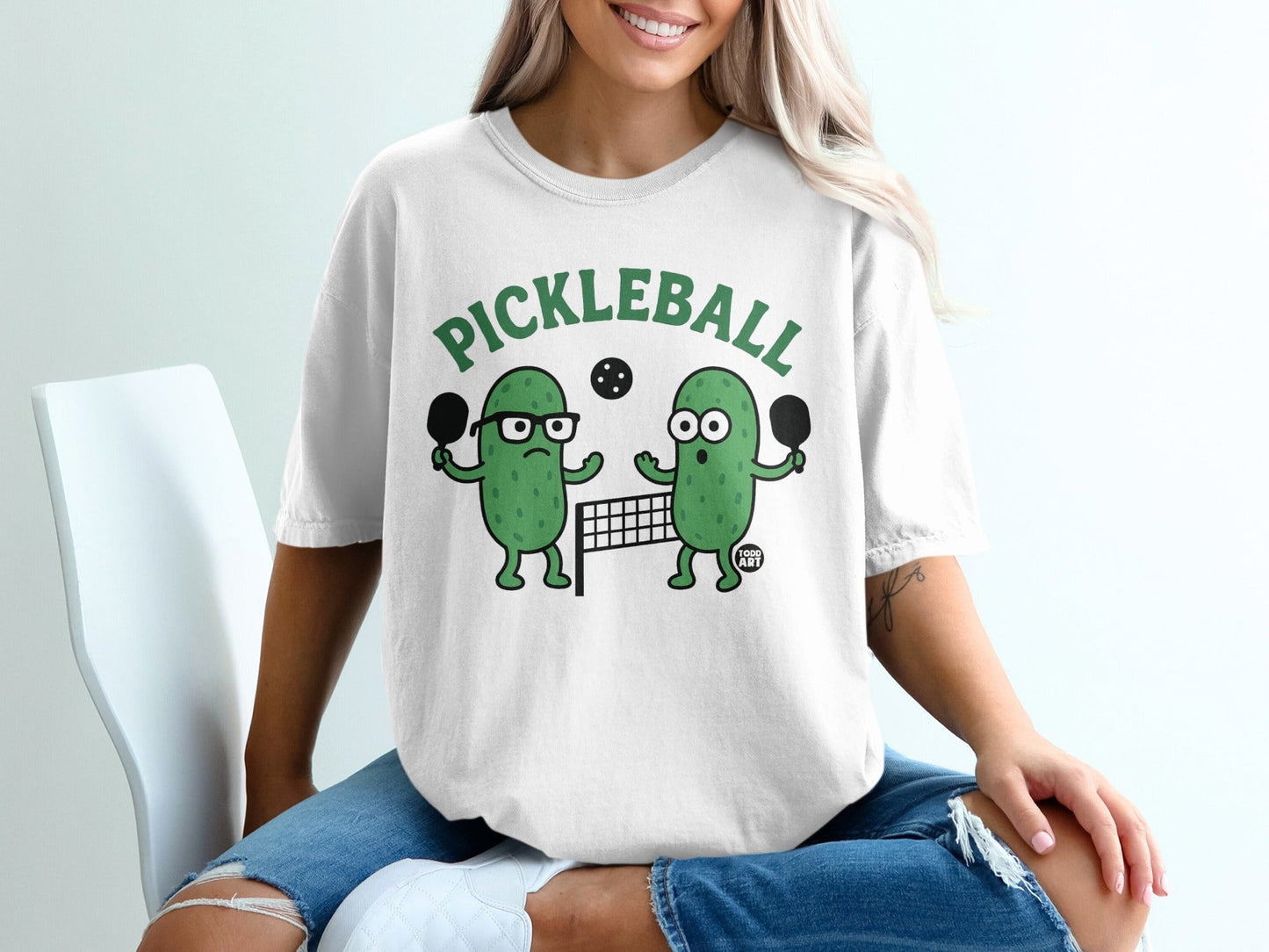 Two cartoon pickles playing pickleball on a court with net and paddles.