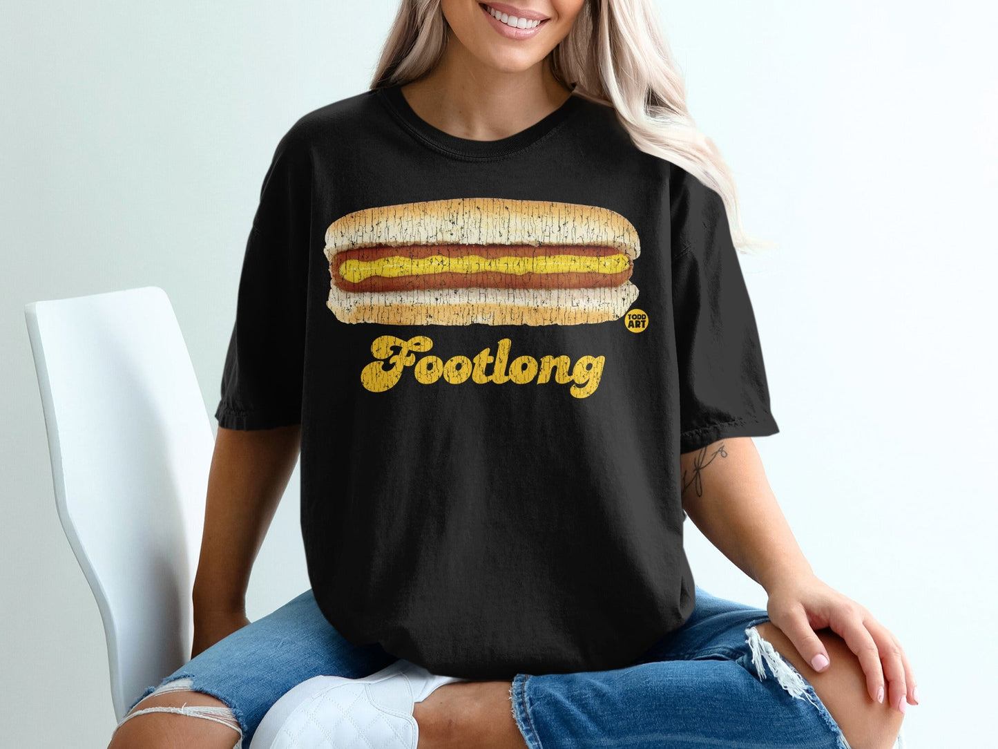 Black t-shirt with a distressed yellow "FOOTLONG" hot dog graphic.