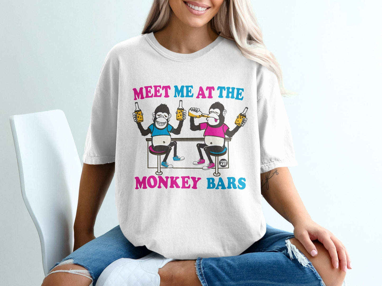 White t-shirt with "MEET ME AT THE MONKEY BARS" and two cartoon monkeys drinking beer.