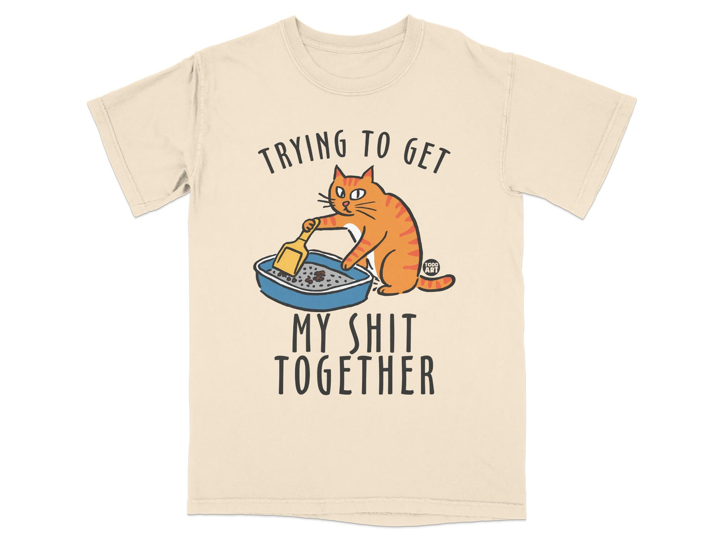 Cream t-shirt with cartoon cat cleaning litter box, text "Trying to Get My Shit Together".