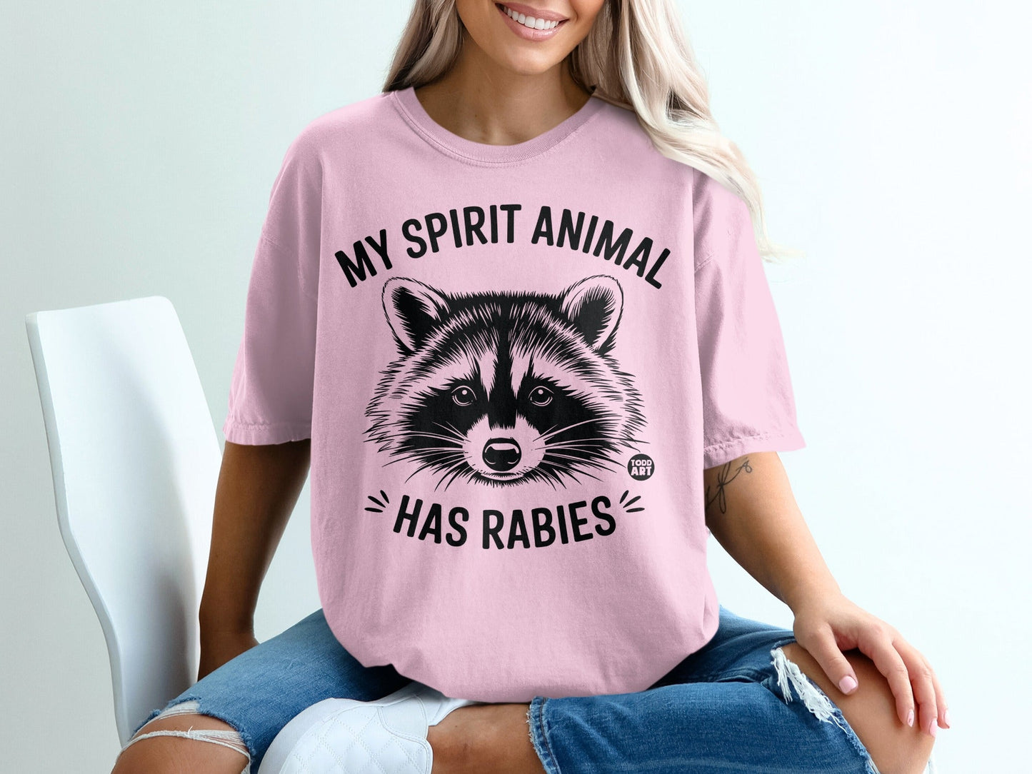 Pink t-shirt with raccoon graphic and "My spirit animal has rabies" text.
