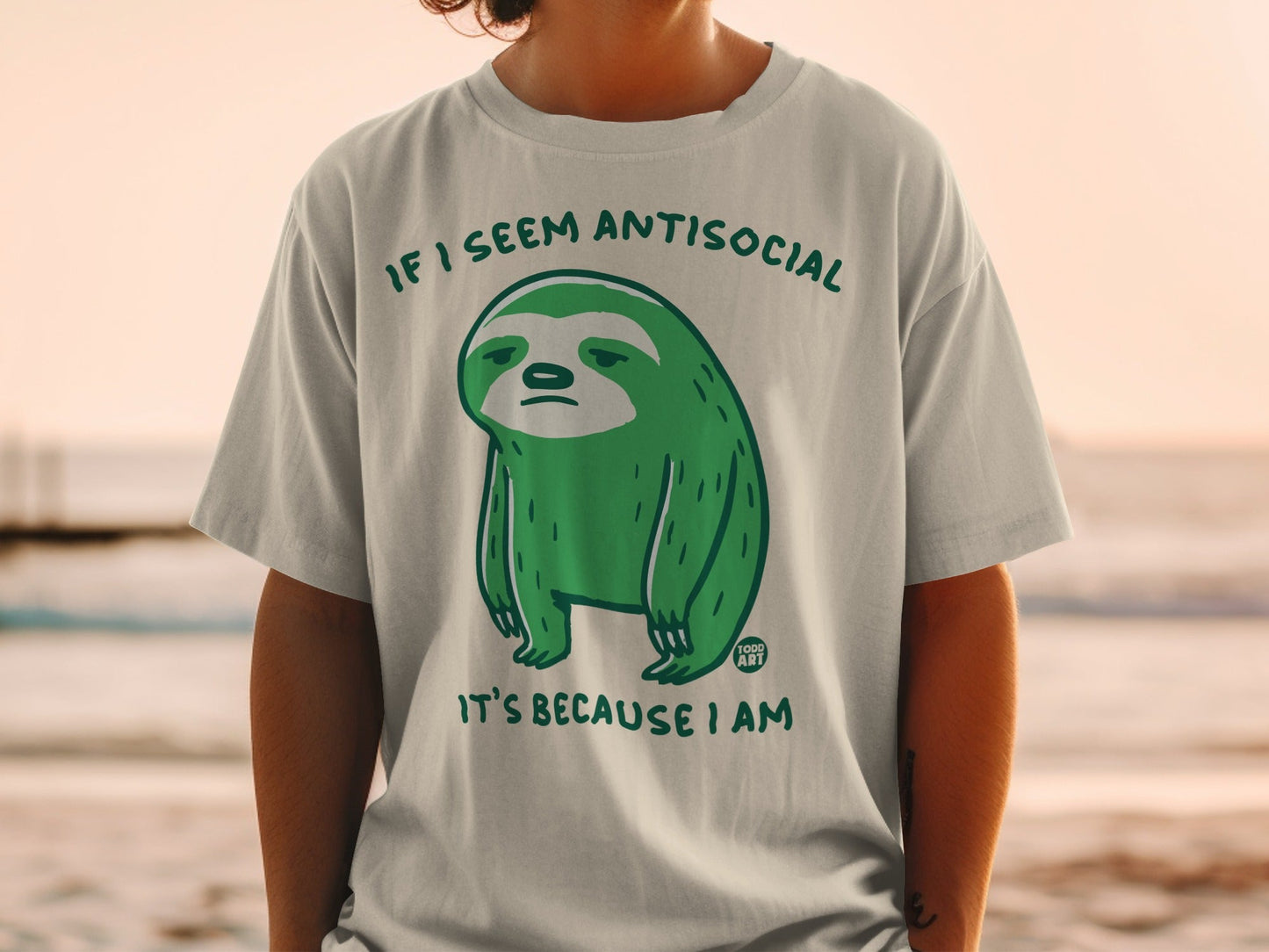 Green sloth wearing a t-shirt that says "If I seem antisocial it's because I am."