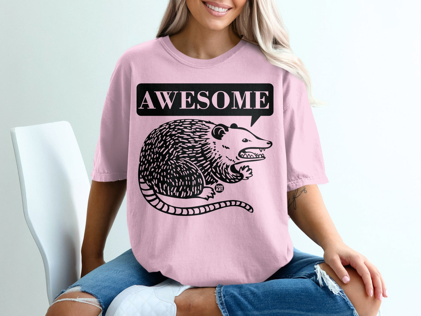 Pink t-shirt with a black opossum and "AWESOME" speech bubble graphic.