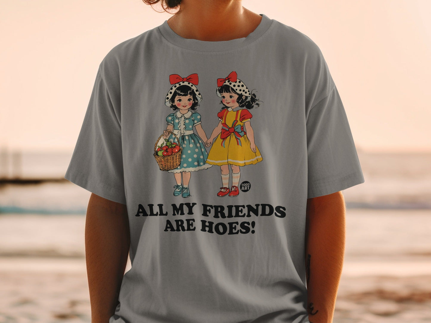 Grey t-shirt with vintage cartoon girls holding hands, one with a basket of apples.