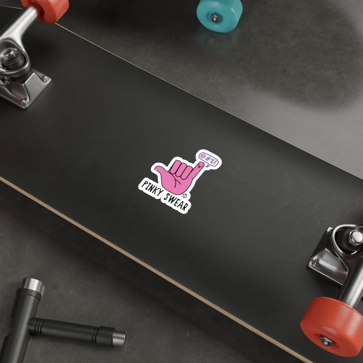 Pinky Swear Sticker on Black Skateboard Deck