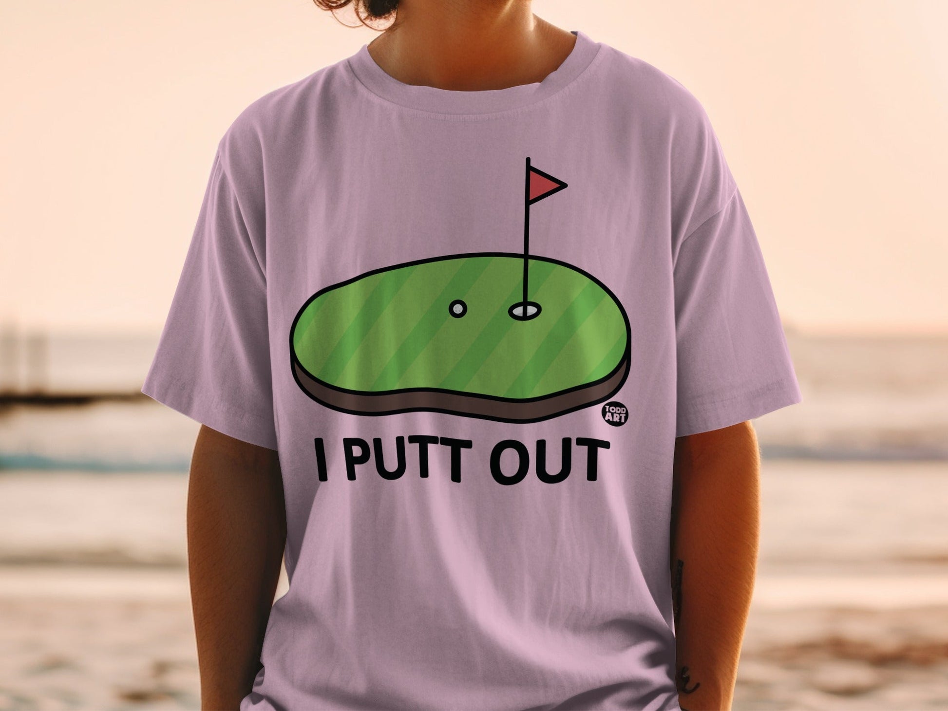 Purple t-shirt with "I PUTT OUT" text and a golf putting green graphic.