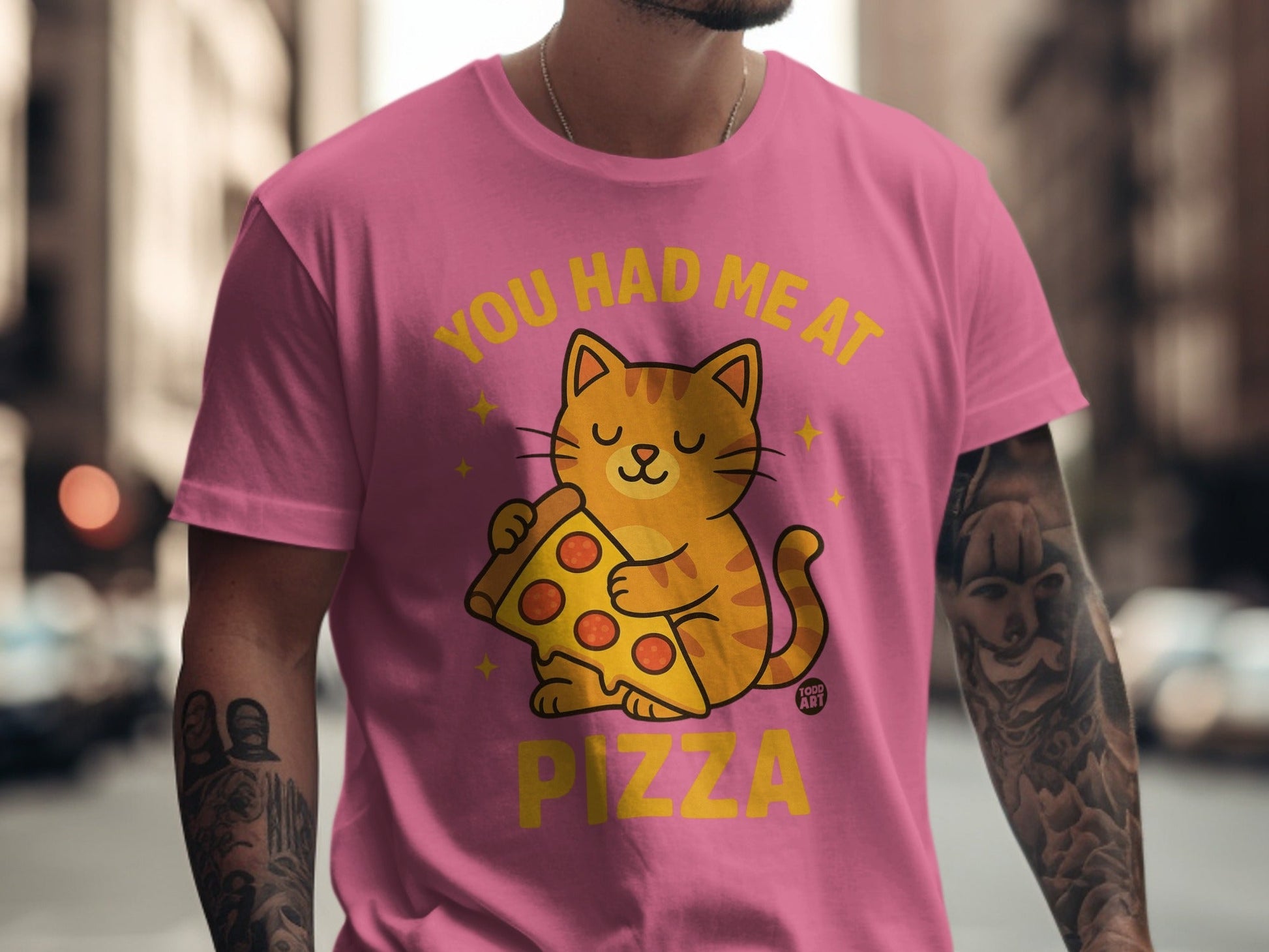 Pink t-shirt with a cartoon cat holding a slice of pizza, text reads "You had me at Pizza".