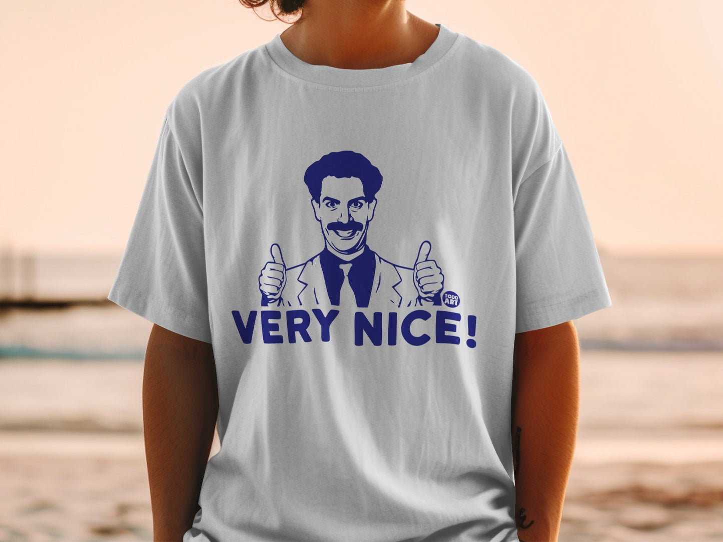 White t-shirt with navy blue graphic of Borat giving two thumbs up saying "VERY NICE!".