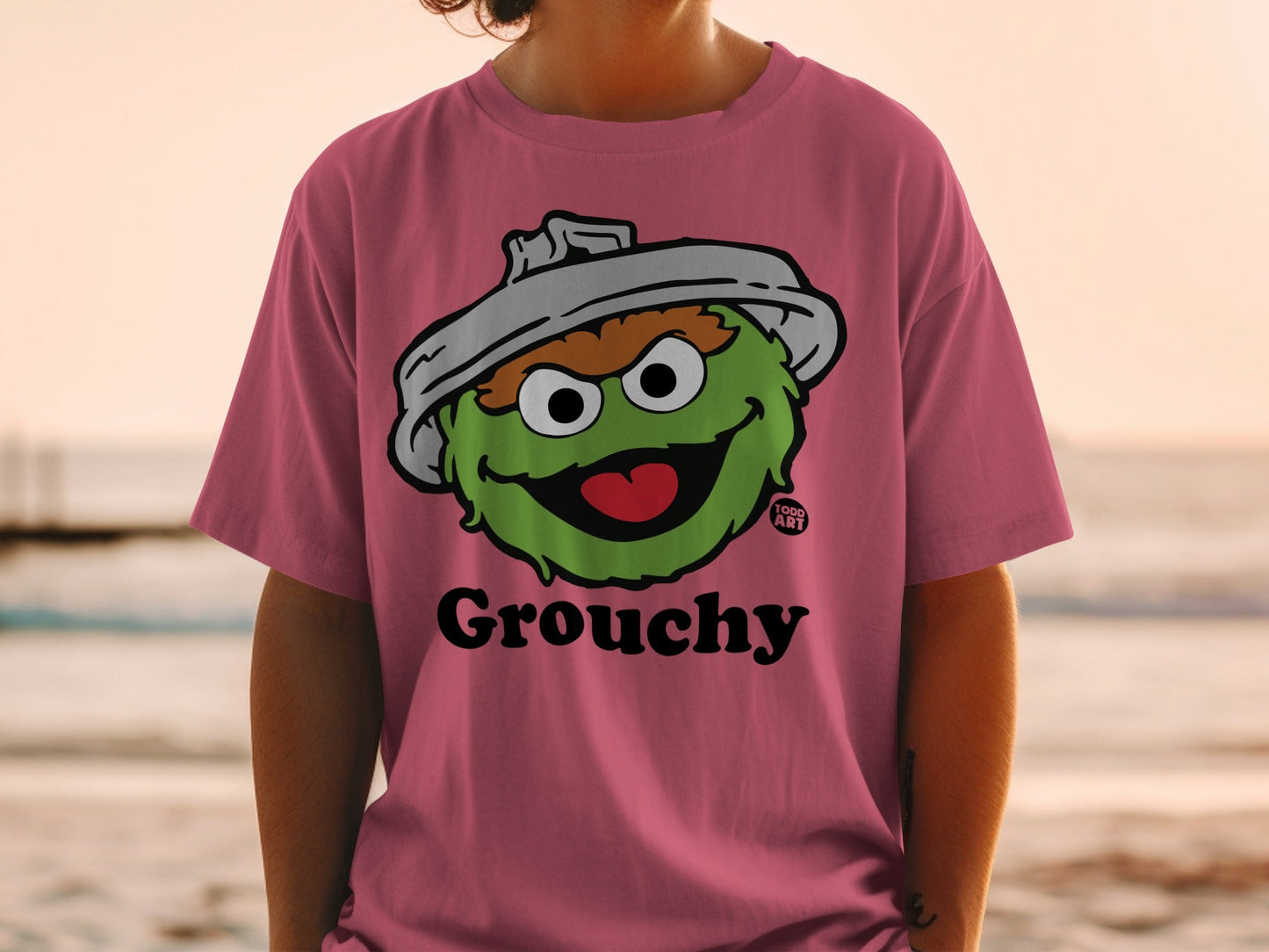 Pink t-shirt with a cartoon drawing of Oscar the Grouch and "Grouchy" text.