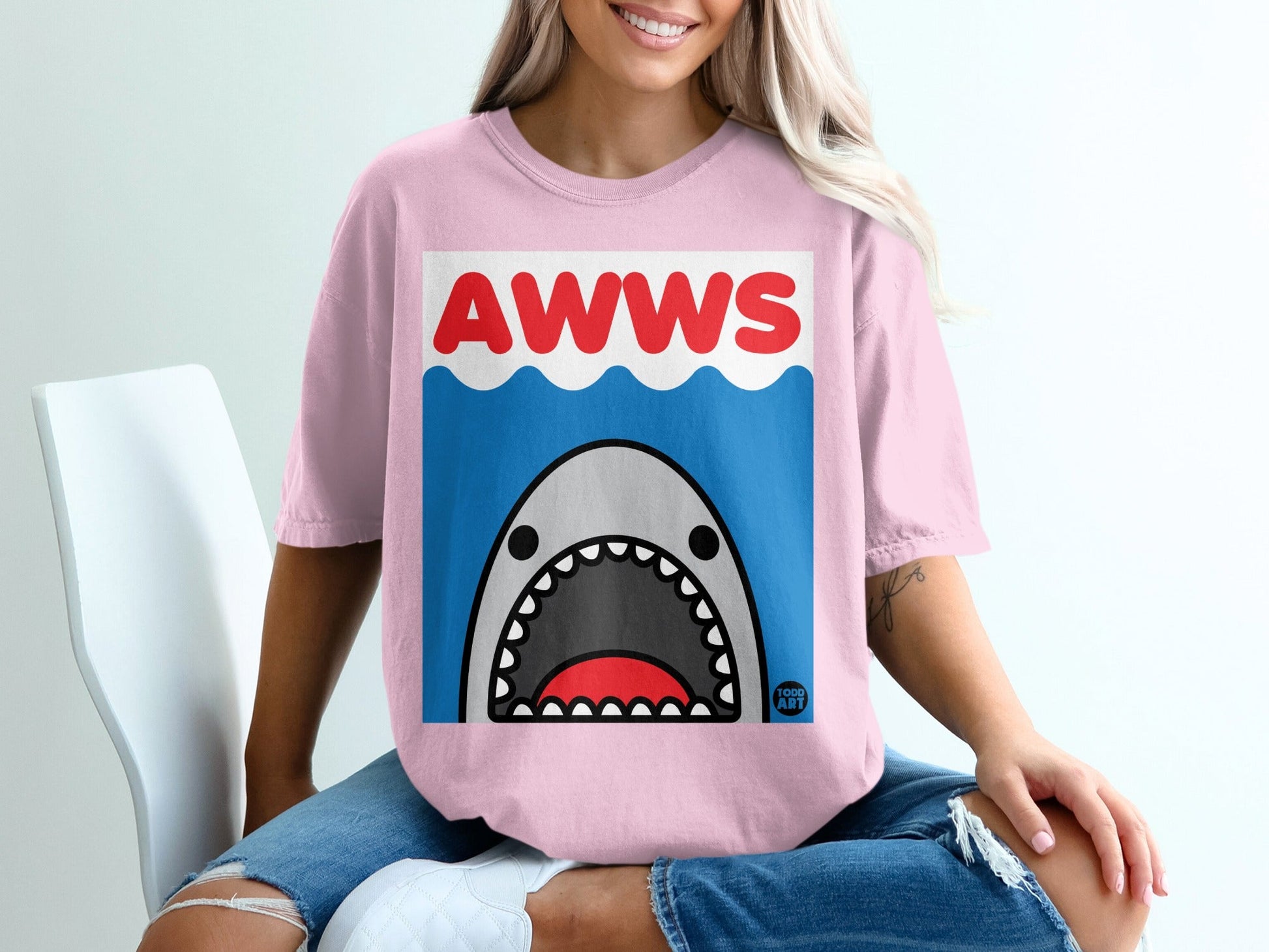 Pink t-shirt with cartoon shark and "AWWS" text.