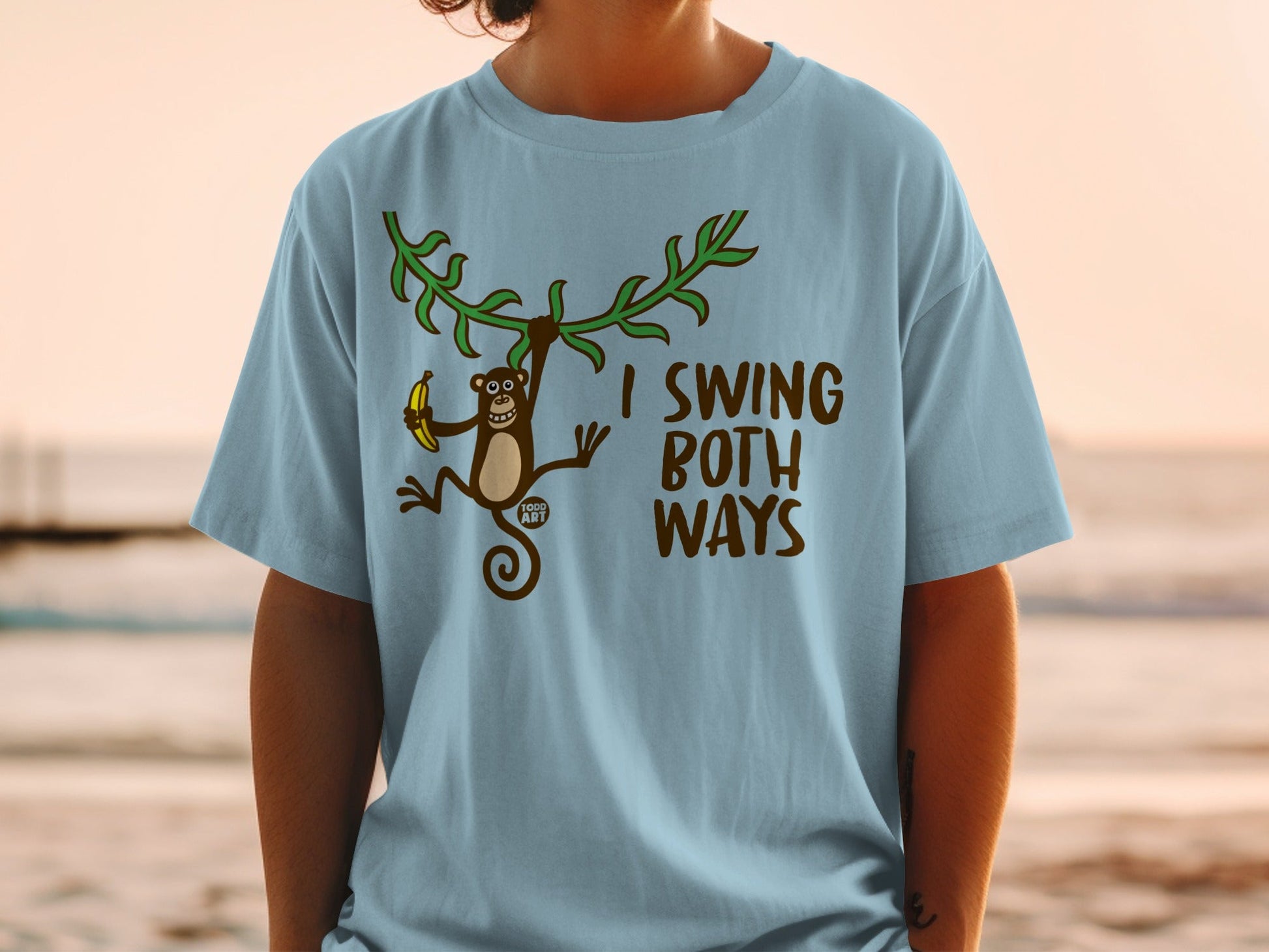 Light blue t-shirt with a cartoon monkey holding a banana and brown text.
