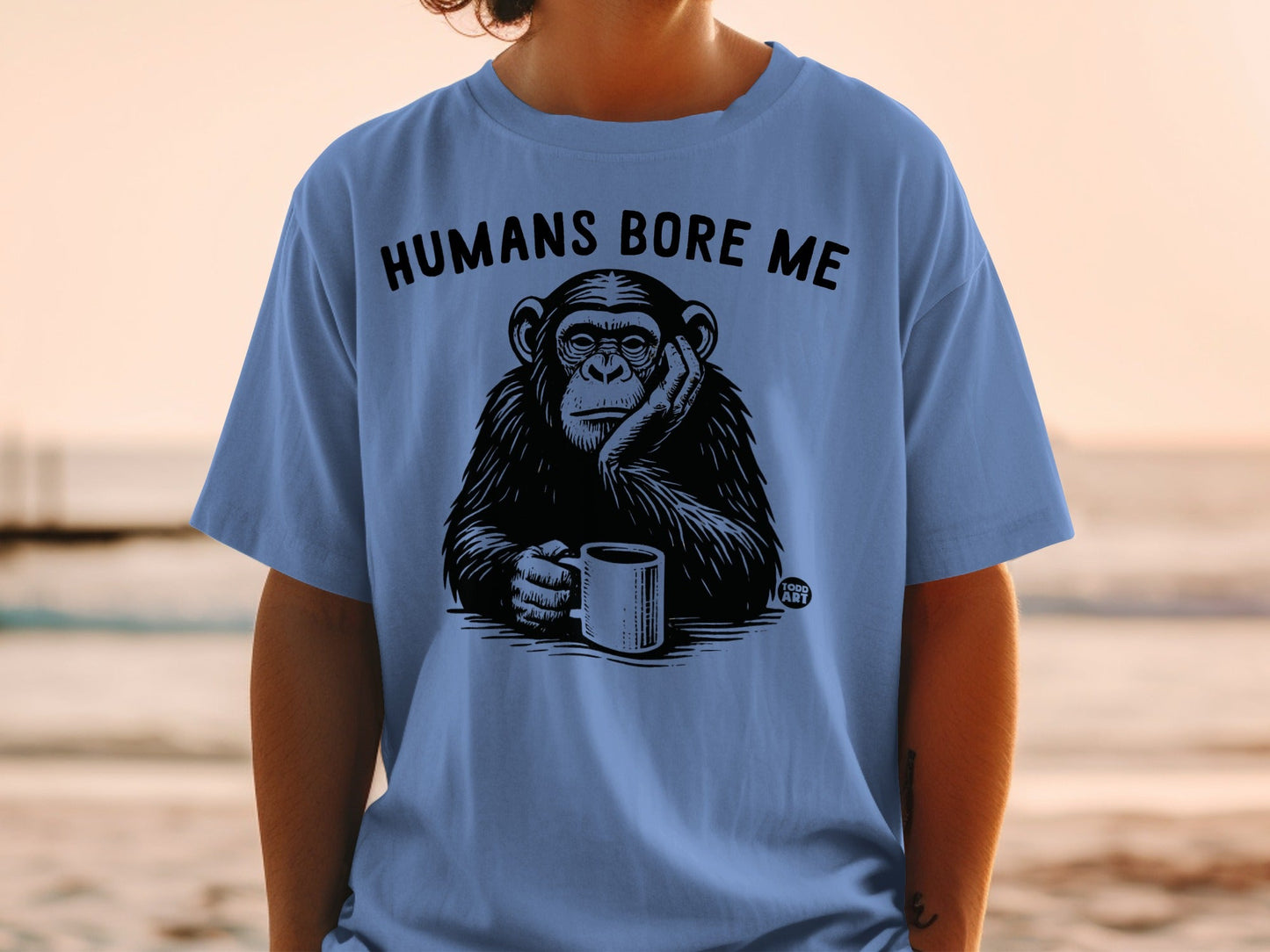 Black and white chimpanzee wearing a t-shirt that says "HUMANS BORE ME".
