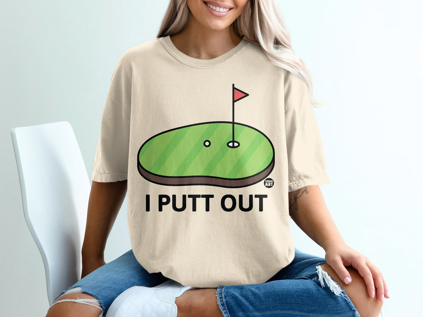 T-shirt with cartoon golf putting green and "I PUTT OUT" text.