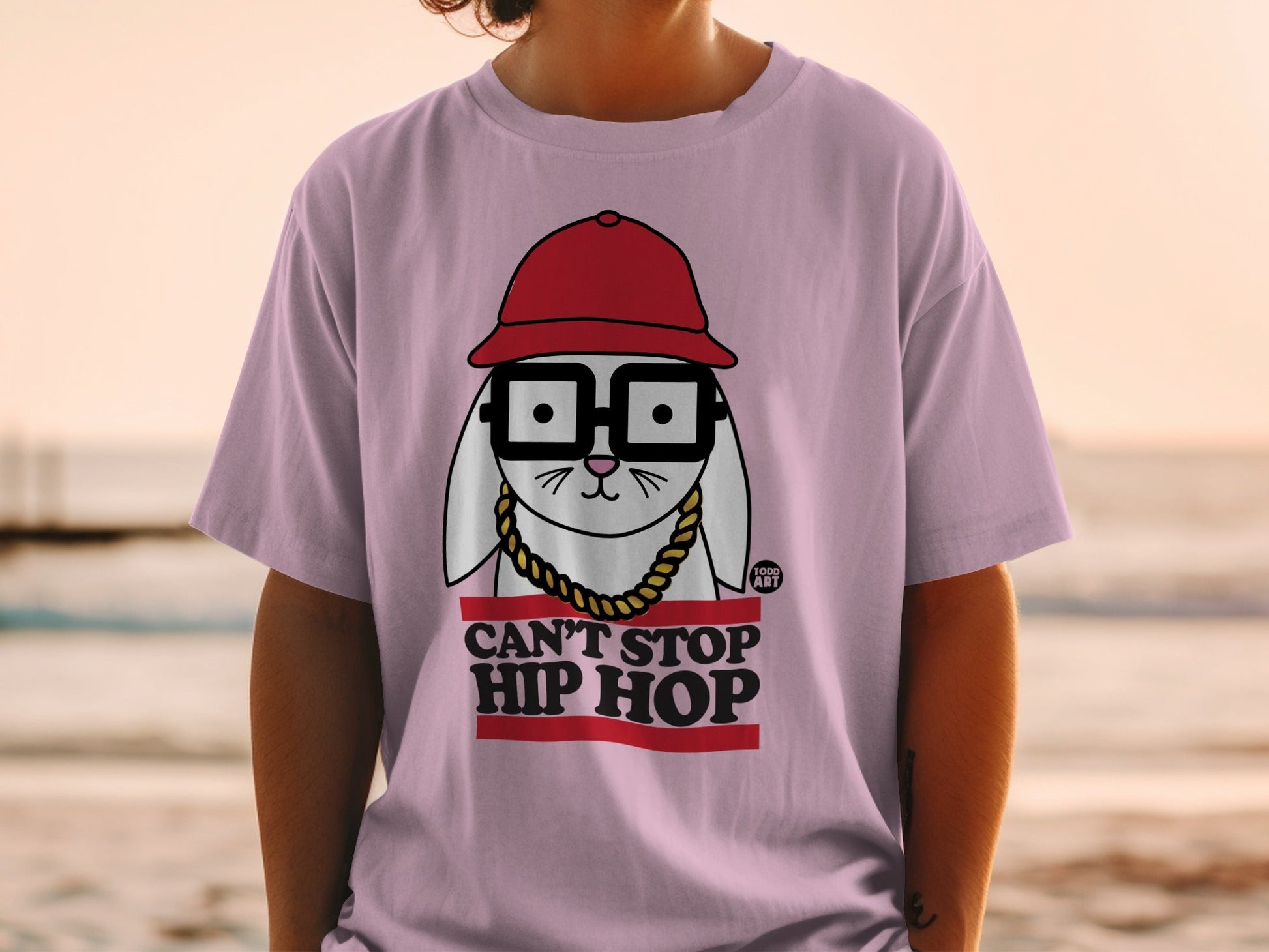 Pink t-shirt with cartoon rabbit wearing glasses, red hat, and gold chain, text "CAN'T STOP HIP HOP".