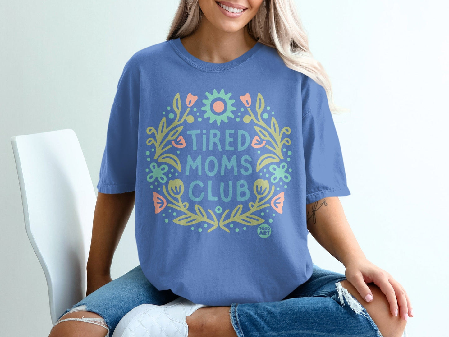 Blue t-shirt with floral wreath and "Tired Moms Club" text.