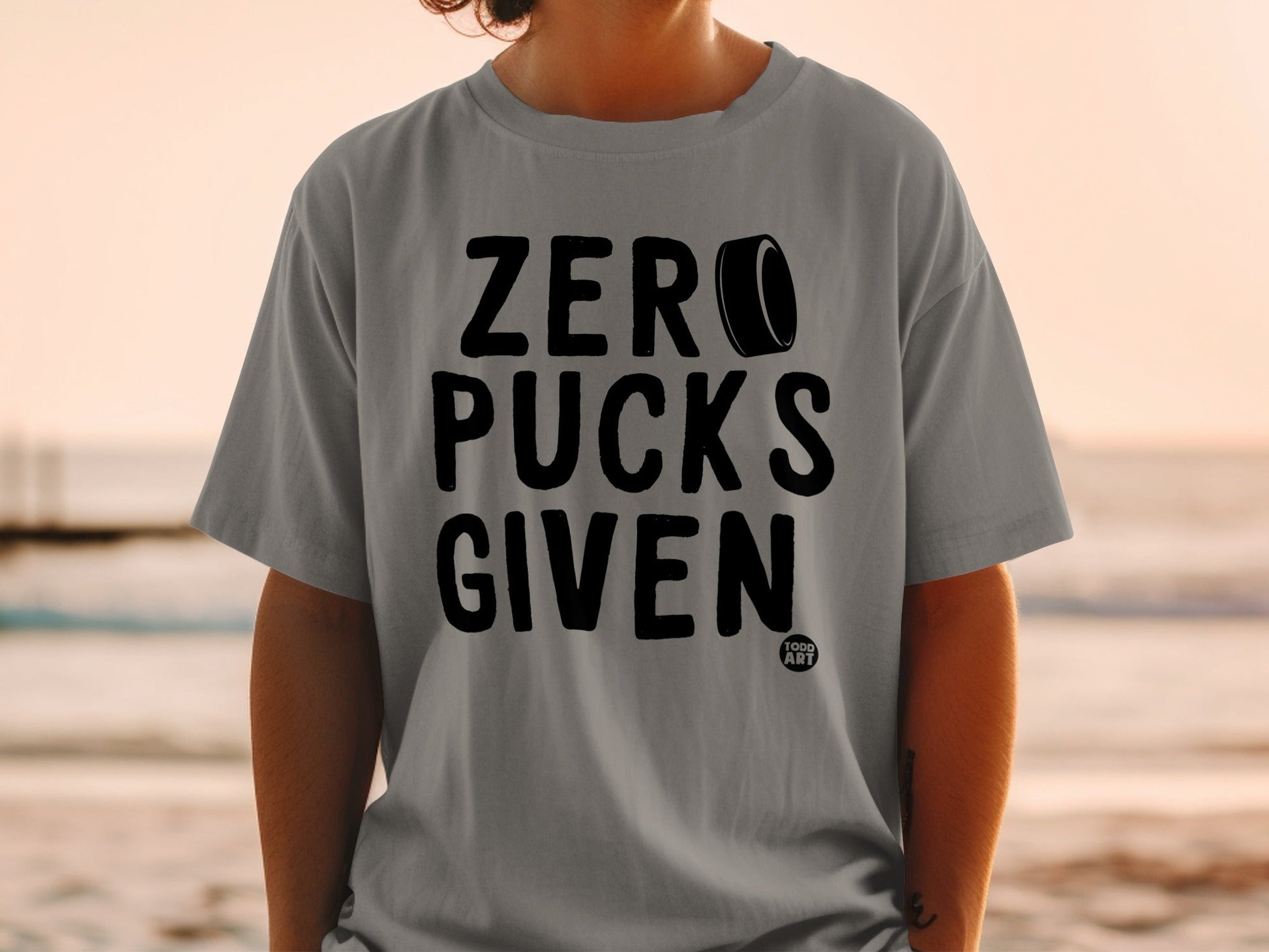 Gray t-shirt with "ZERO PUCKS GIVEN" text and hockey puck graphic.