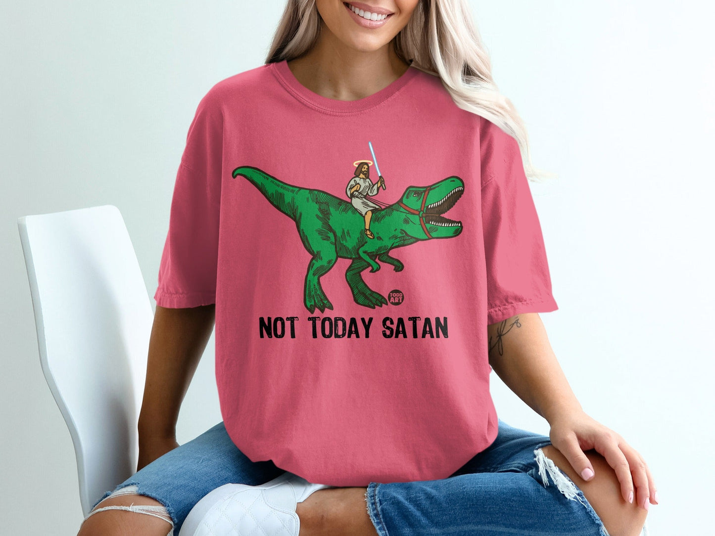 Pink t-shirt with Jesus riding a green dinosaur, text reads "NOT TODAY SATAN".