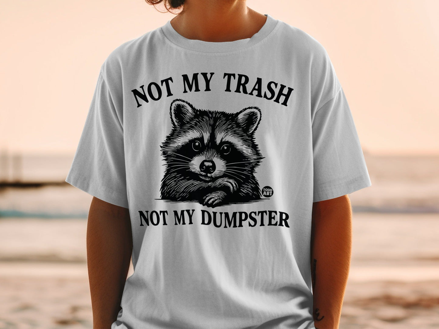 White t-shirt with raccoon graphic and text: NOT MY TRASH, NOT MY DUMPSTER.
