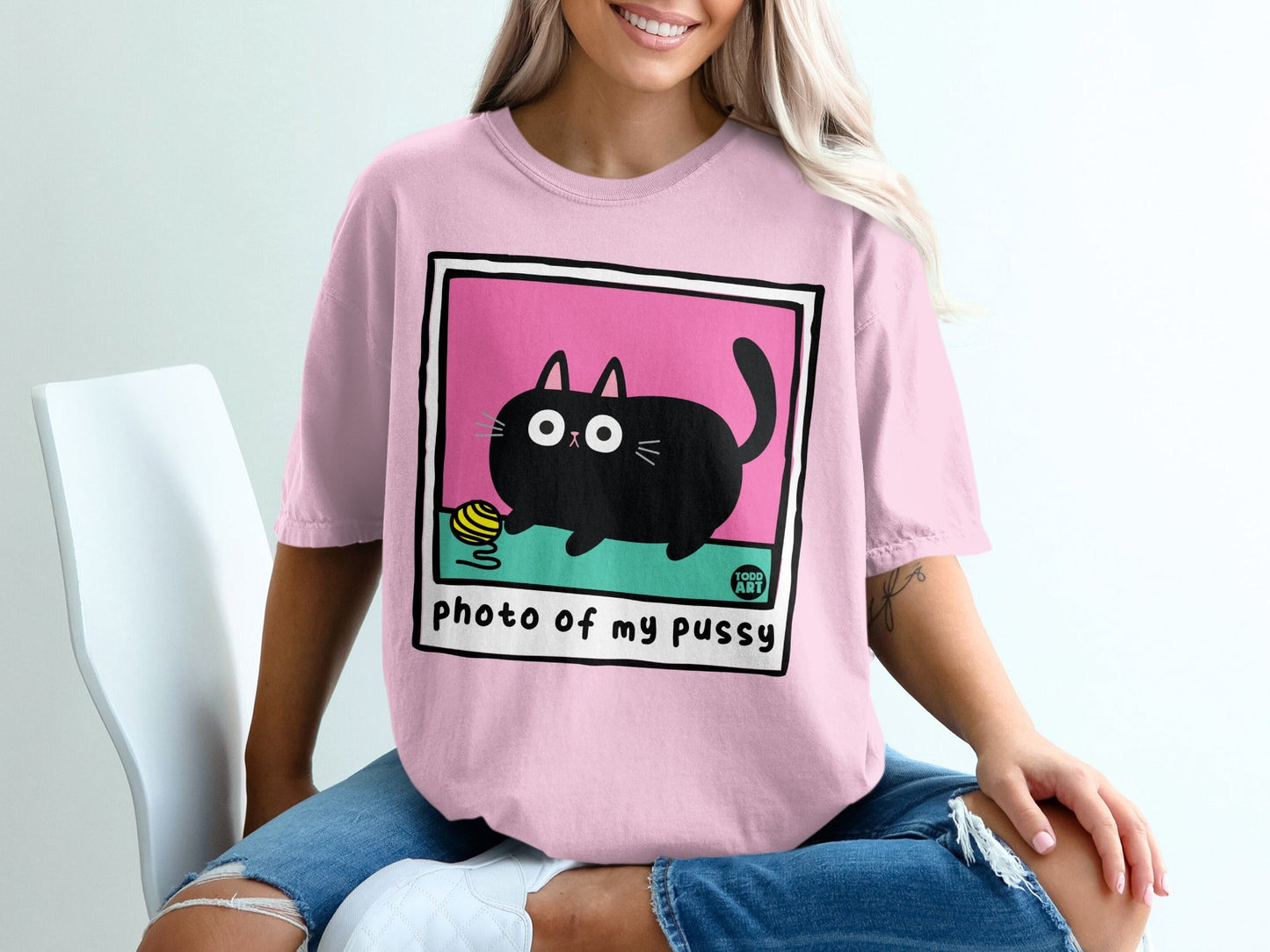 Pink t-shirt with "photo of my pussy" text and cartoon cat with yarn ball.