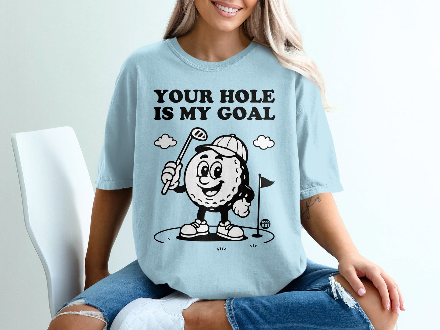 Light blue t-shirt with cartoon golfer and text "YOUR HOLE IS MY GOAL".