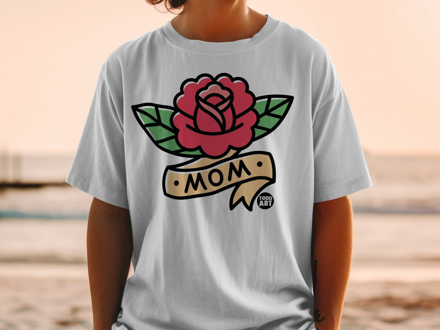 White t-shirt with a rose tattoo design that says "MOM" on a banner.