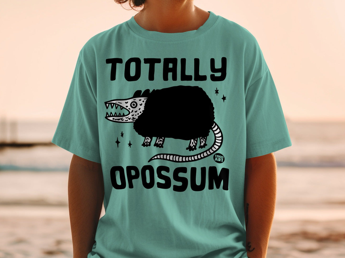 Teal t-shirt with a black opossum graphic and text "Totally Opossum".