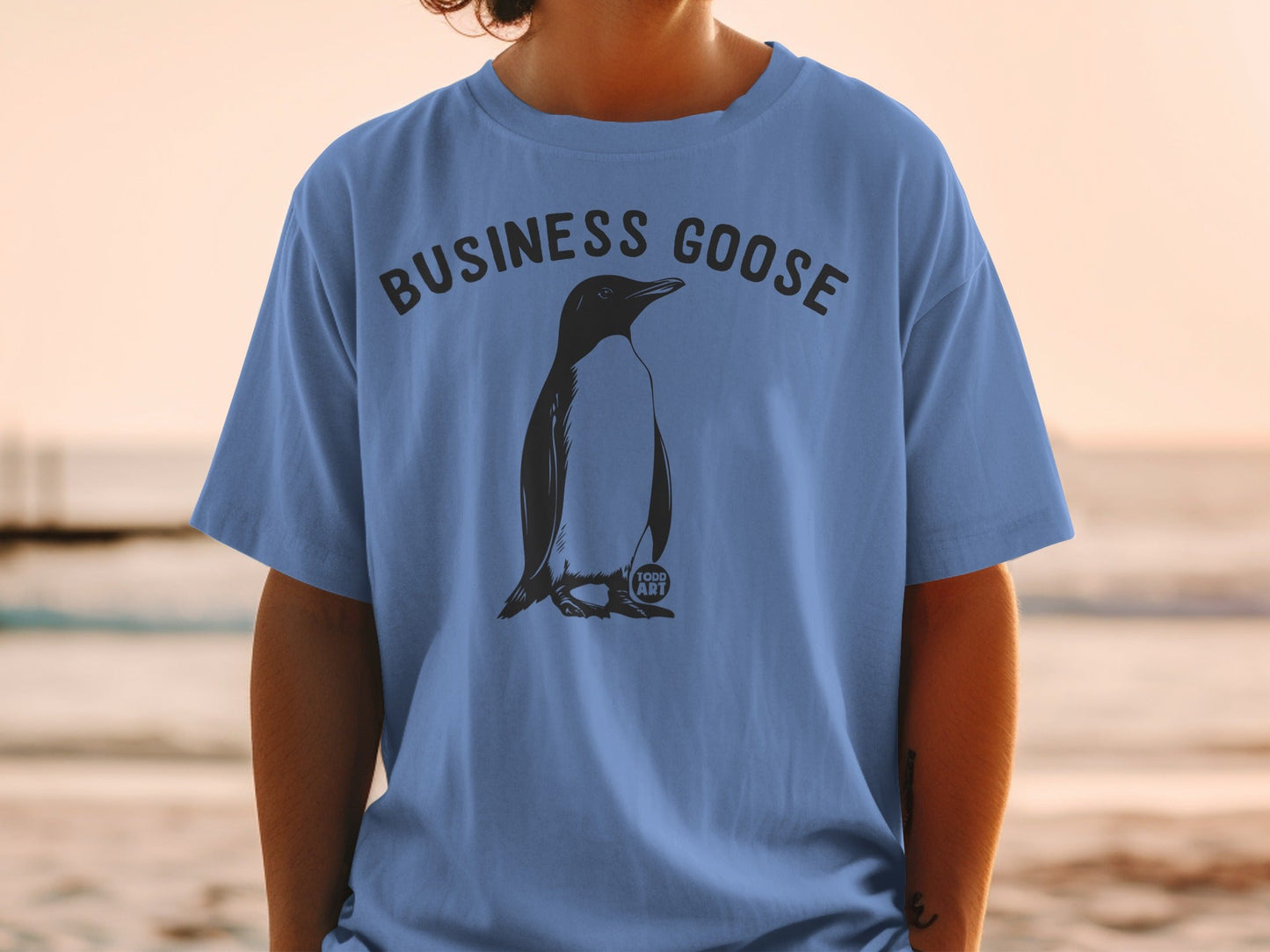 T-shirt with "BUSINESS GOOSE" text and penguin graphic on blue fabric.