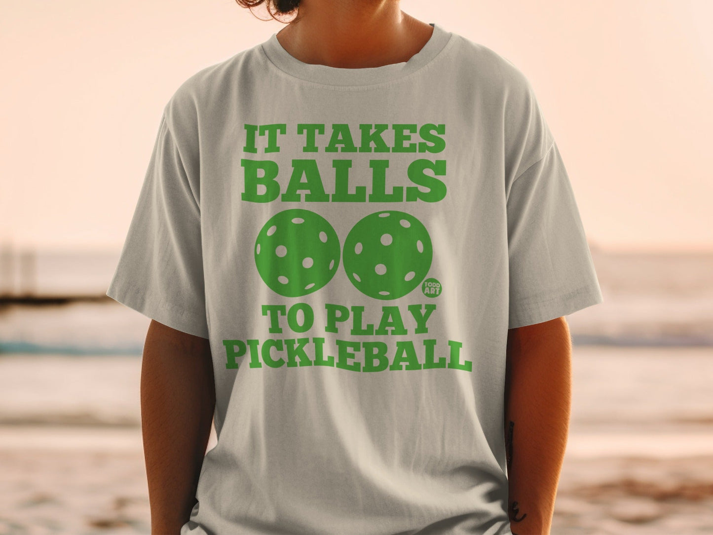 Gray t-shirt with green text "It Takes Balls To Play Pickleball" and two pickleballs.