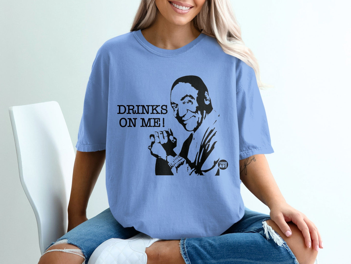 Blue t-shirt with black graphic of a man and text "DRINKS ON ME!".