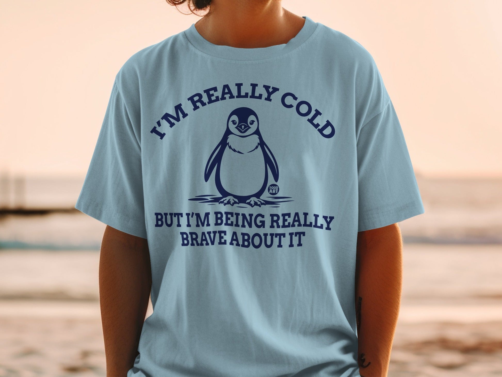 Light blue t-shirt with a penguin and text that reads "I'M REALLY COLD BUT I'M BEING REALLY BRAVE ABOUT IT".