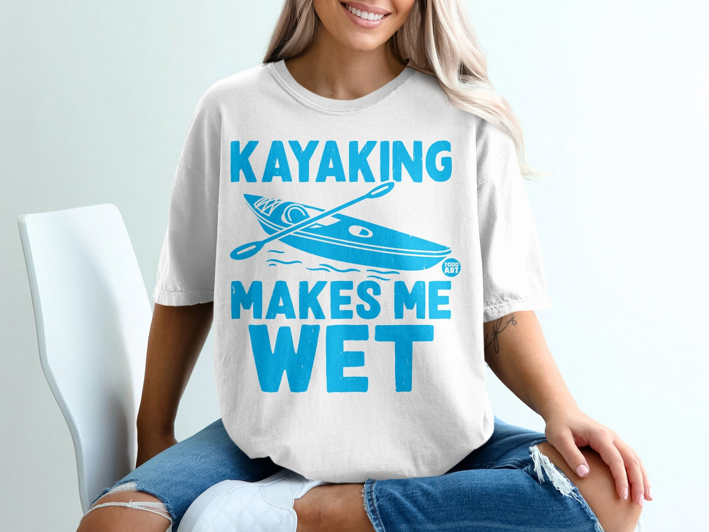 White t-shirt with blue text and kayak graphic that says "Kayaking Makes Me Wet".