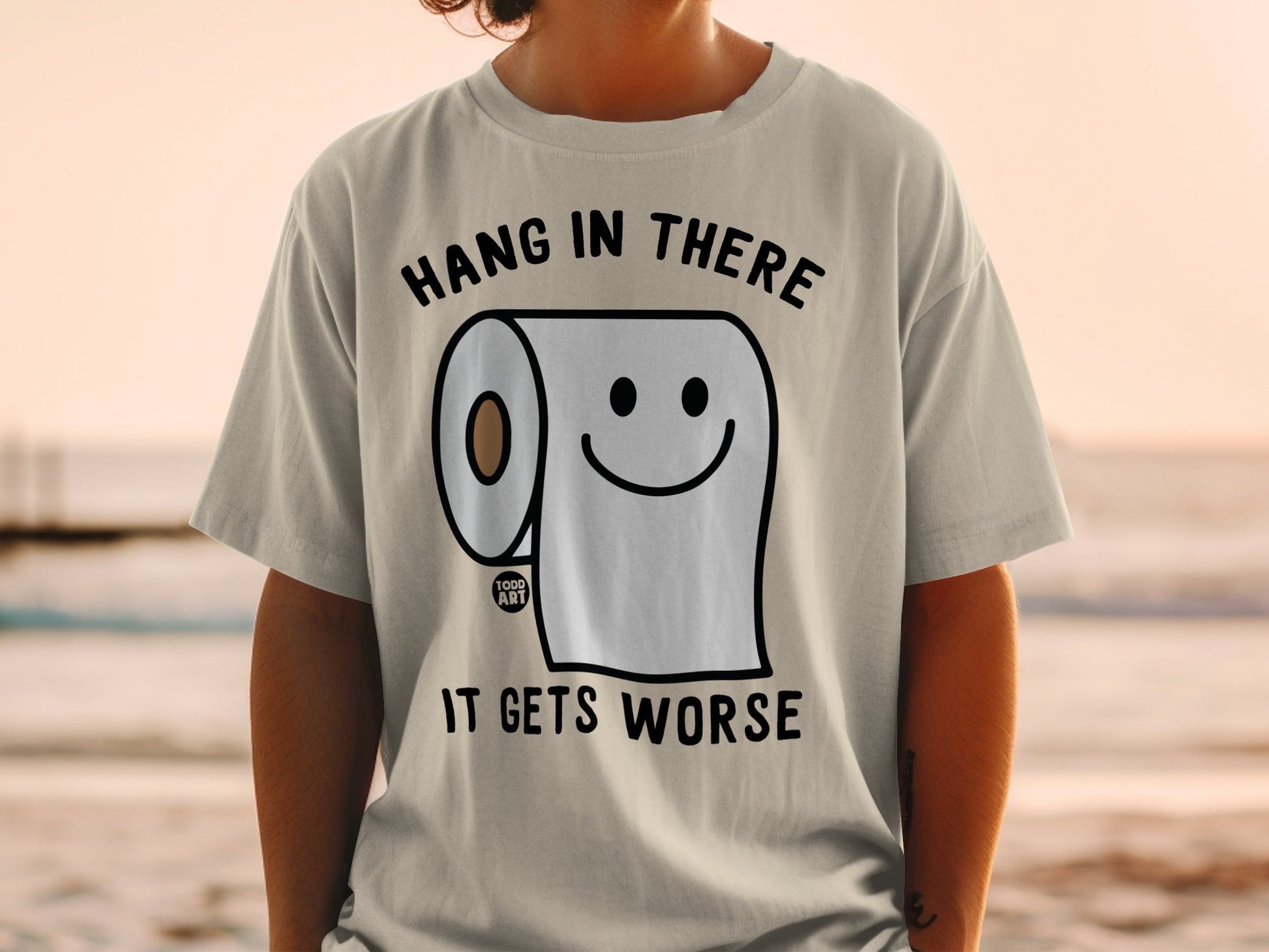 T-shirt with a roll of toilet paper and the text "HANG IN THERE IT GETS WORSE".