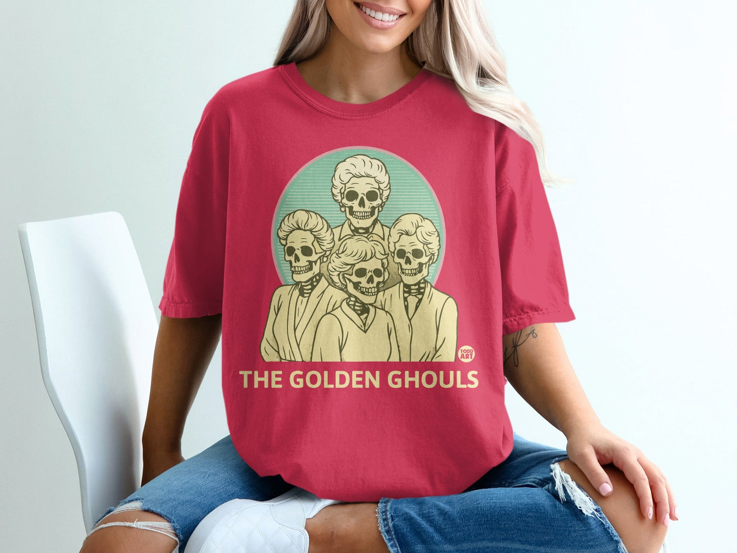 Red t-shirt featuring four skeleton heads in a circular design with text "THE GOLDEN GHOULS".