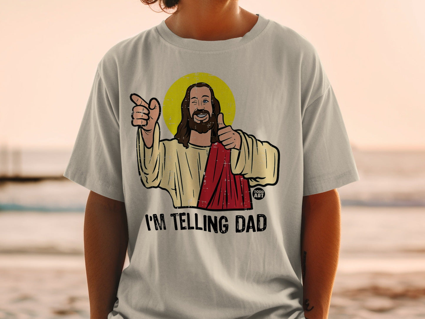 T-shirt with Jesus giving a thumbs up and pointing, text reads "I'M TELLING DAD".