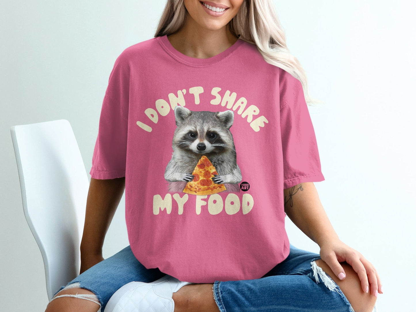 Pink t-shirt with raccoon holding slice of pizza and text "I don't share my food".