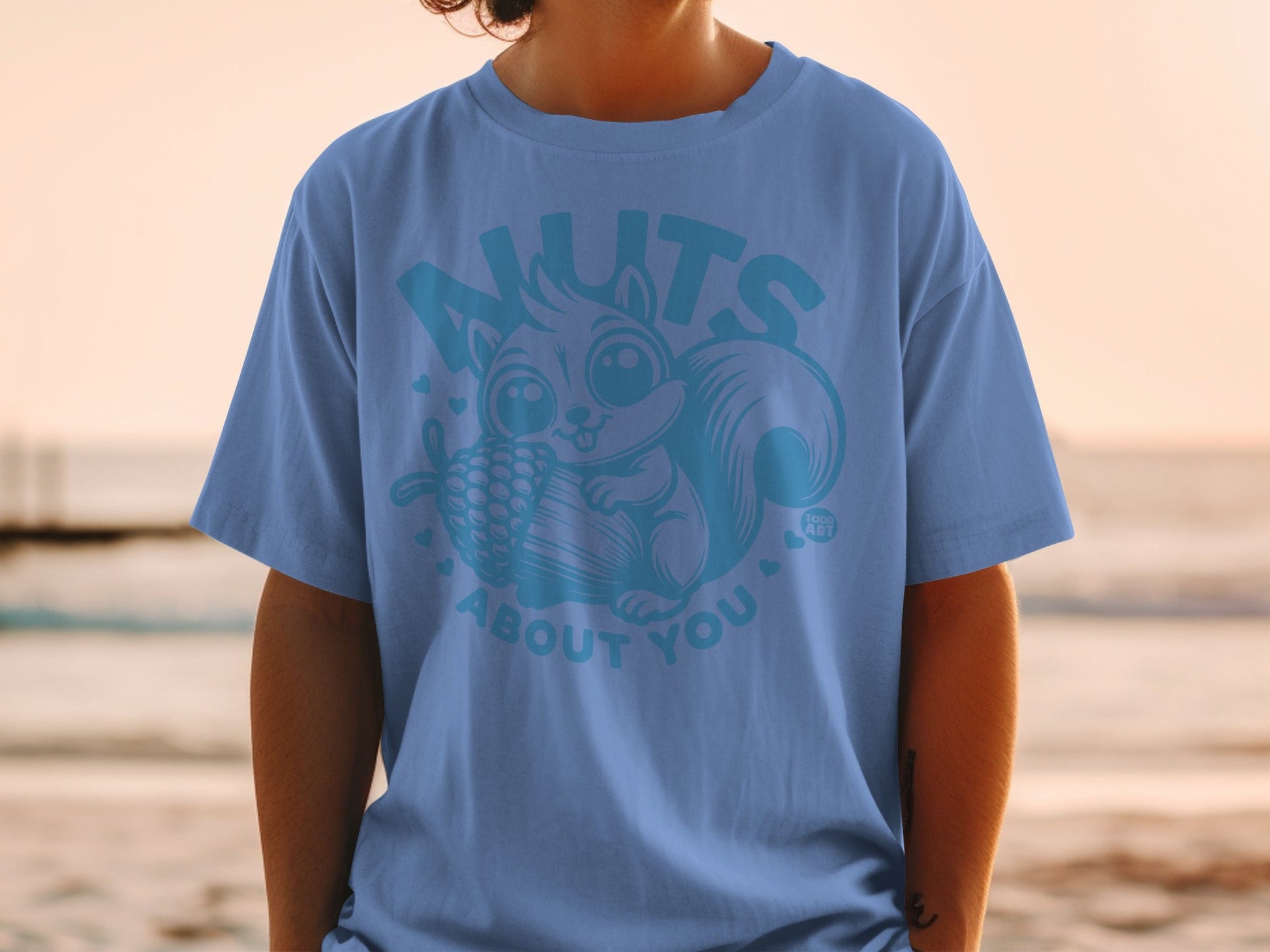 Light blue t-shirt with cartoon squirrel holding a pinecone and text "NUTS ABOUT YOU".