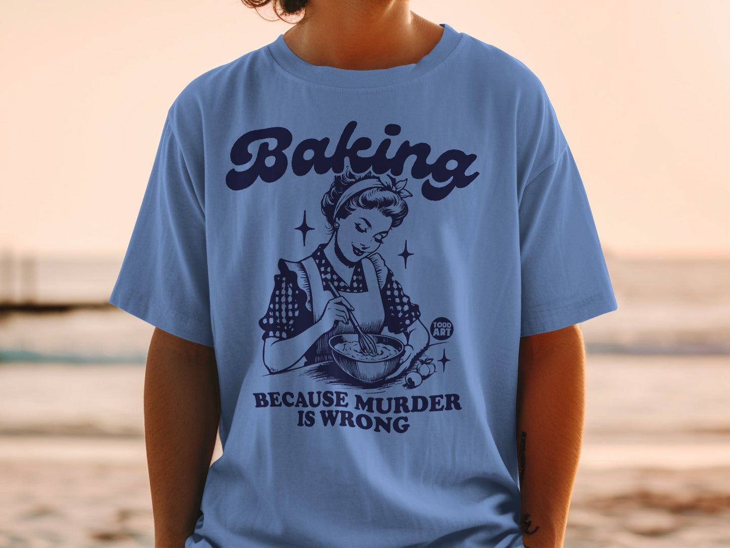 Blue t-shirt with vintage illustration and text "Baking because murder is wrong".