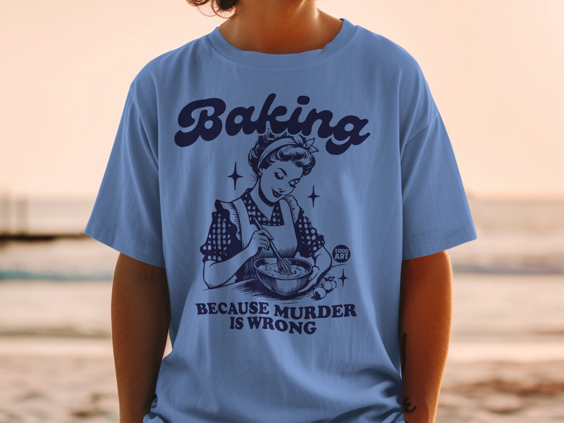 Blue t-shirt with vintage illustration and text "Baking because murder is wrong".