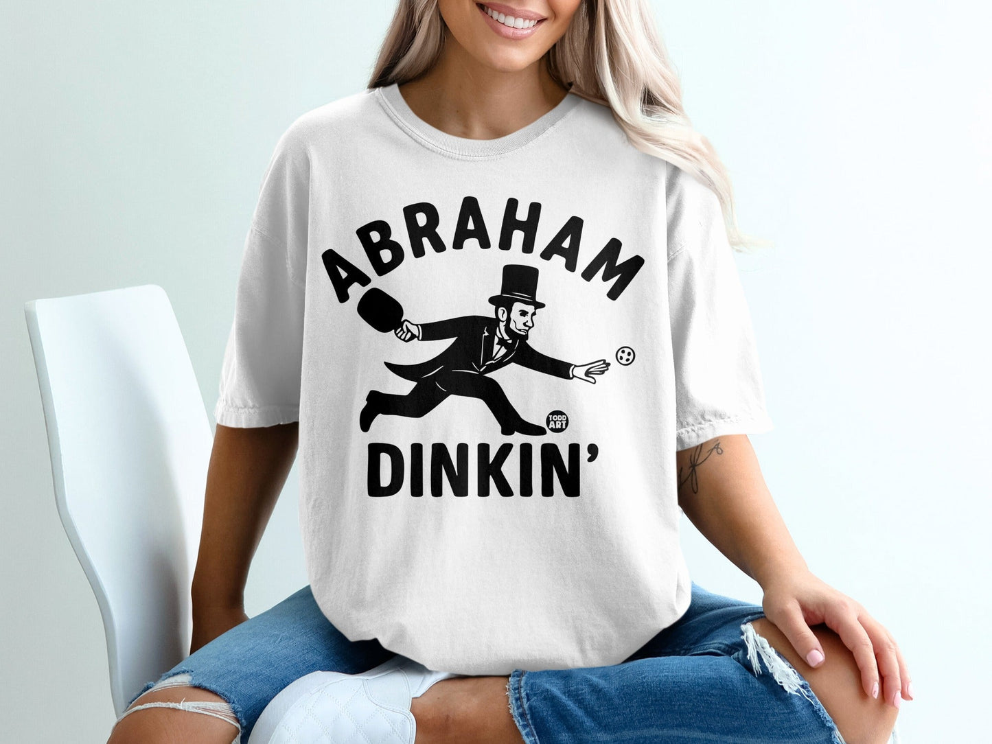 T-shirt with "Abraham Dinkin'" and a cartoon man playing paddleball.