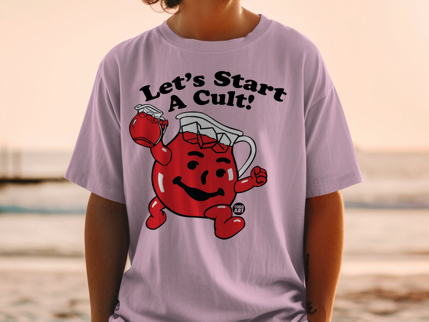 Kool-Aid pitcher character on light purple t-shirt with "Let's Start A Cult!" text.
