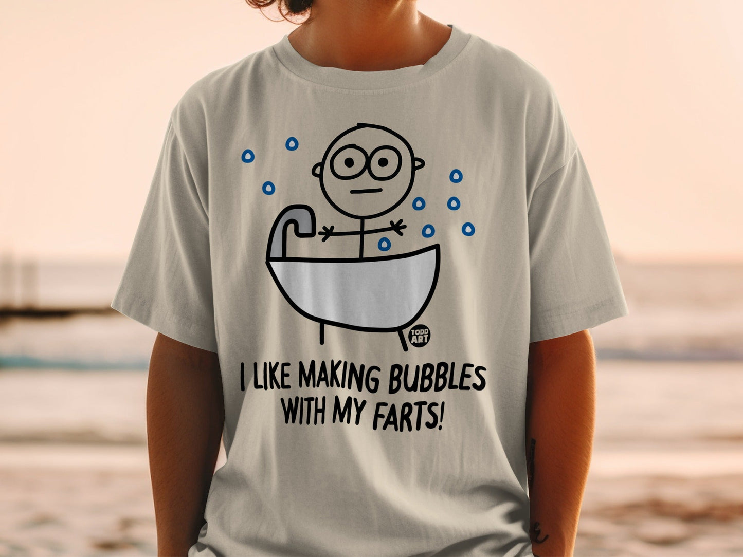 Gray t-shirt with cartoon of person in bathtub, text "I LIKE MAKING BUBBLES WITH MY FARTS!".